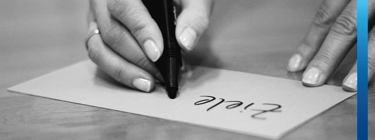 Schwarz-weißes Bild, Frau schreibt auf Moderationskarte den Text Ziele